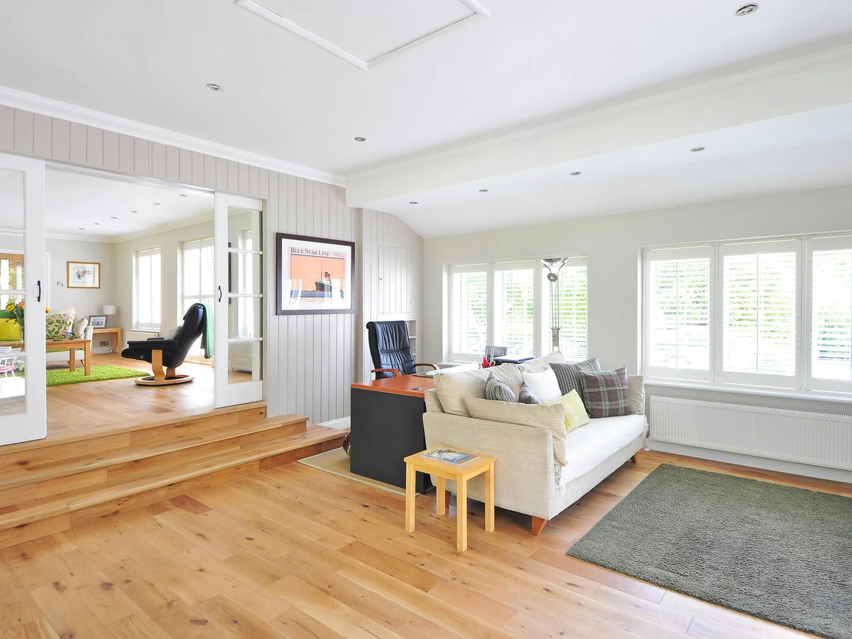 Bright open-plan living room with pale walls and a wooden floor